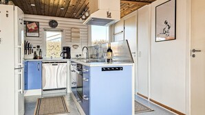 Een kleine keuken met een ingebouwde oven, een koffiezetapparaat en een fles wijn op het aanrecht.