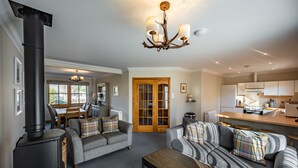 A cozy living room with a fireplace, two sofas, a dining area, and a kitchen. - Delightful highland home in Ballater village (Ballater)