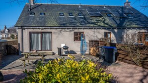 A house with a sloped roof, solar panels, a wooden deck, and a garden area. - Delightful highland home in Ballater village (Ballater)