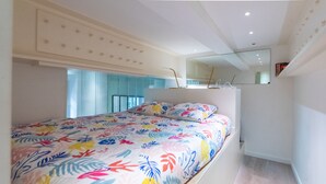 Une chambre à coucher moderne avec un grand lit, un miroir au-dessus du lit et une fenêtre avec des stores.
