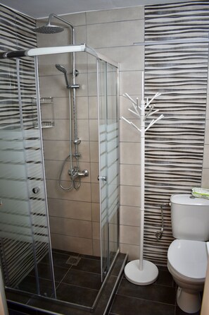 A modern bathroom with a glass-enclosed shower, a toilet, and a patterned wall.