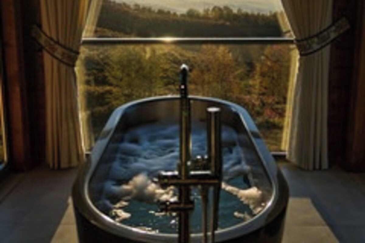 A room with a large window, a bathtub, and curtains.