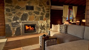 A stone fireplace with a fire, a sofa, and a small table with a plant.