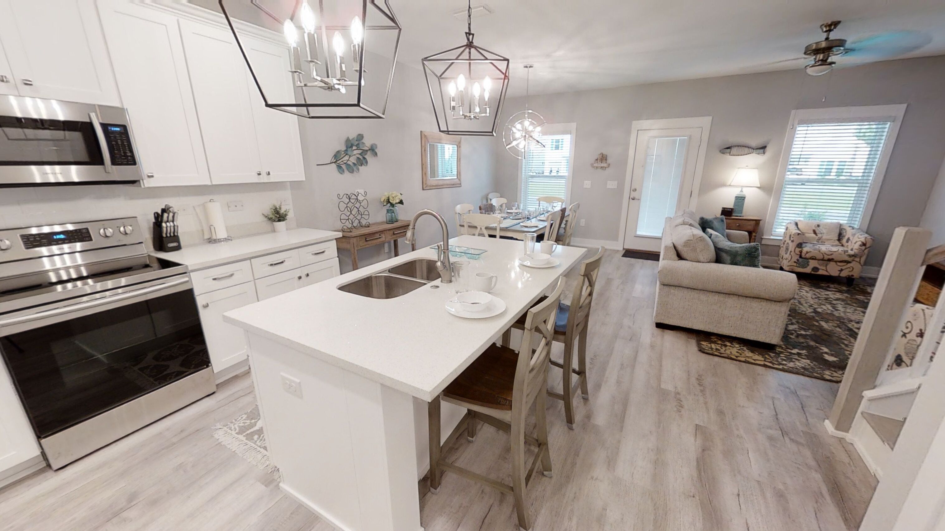 A modern kitchen with white cabinetry, stainless steel appliances, and a central island with a sink.
