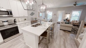 Una cocina moderna con armarios blancos, electrodomésticos de acero inoxidable y una isla central con fregadero.
