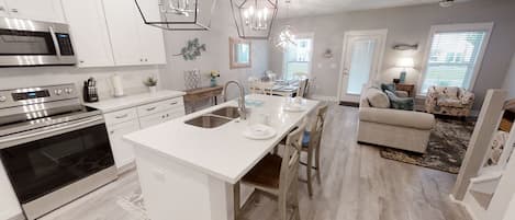 Een moderne keuken met witte kasten, roestvrijstalen apparatuur en een centraal kookeiland met spoelbak.