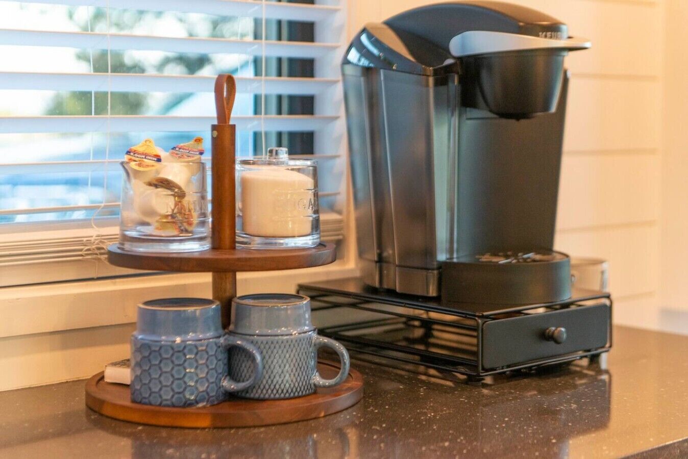 A coffee maker on a kitchen counter with a window in the background.