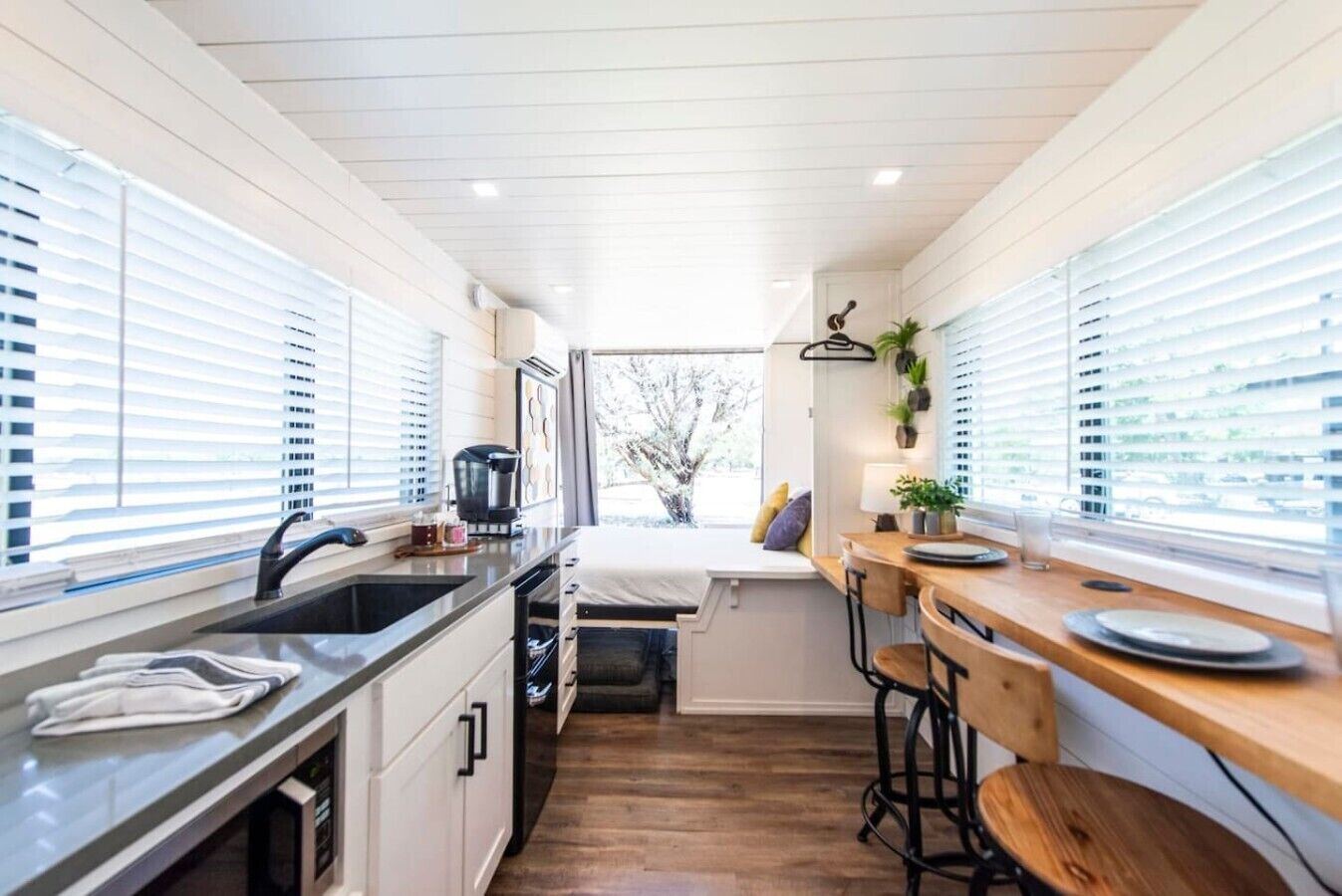 A compact kitchen with a sink, stove, and bar stools.
