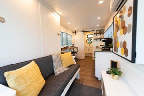 Espaço compacto com sofá, cozinha compacta e área de jantar.