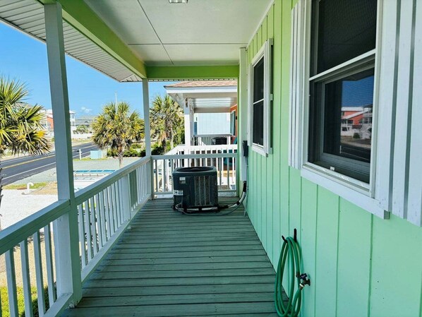 A green building with a covered porch, a window, and a hose. - Oceanfront Lime Inn, 4BR home in Holden Beach, sleeps 9, perfect for families. (Holden Beach)
