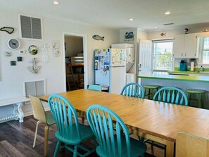 A kitchen with a wooden table and chairs, a refrigerator, and various wall decorations.