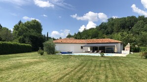 Ein Haus mit einem Ziegeldach, einem Swimmingpool und einem Garten.