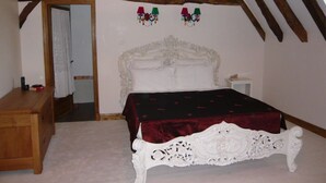 A bedroom with a white ornate bed, a wooden dresser, and a slanted ceiling with exposed beams. - luxury gite for couples, no children. Peace, great views, large pool and spa. (Boisse, France)