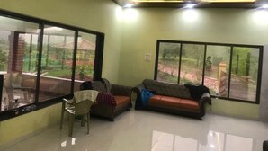 Una habitación con dos sofás, una silla y ventanas amplias que dan a vistas de zonas verdes y un edificio.