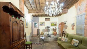 Una sala de estar acogedora con un aparador de madera, un sofá verde, una araña y una chimenea de piedra.
