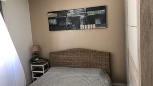 A bedroom with a bed, a nightstand, a lamp, and a wall-mounted abstract painting. - 2-room apartment for 2 people close to Moure Rouge beach. (Cannes)