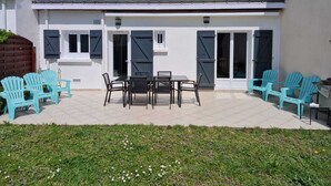 Een huis met een terras, een omheinde tuin en een garage.