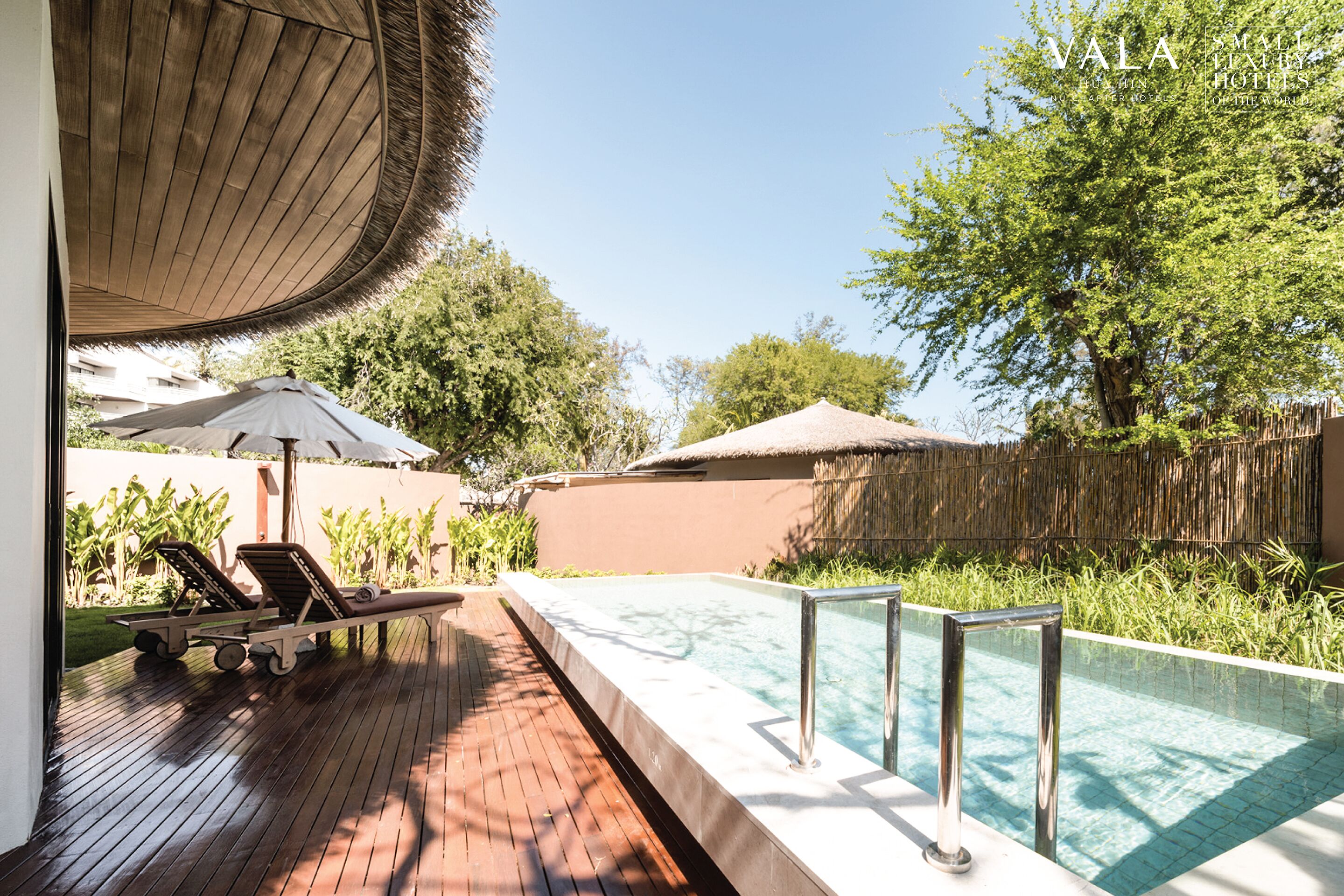 A poolside area with lounge chairs, a pool, and a wooden deck.