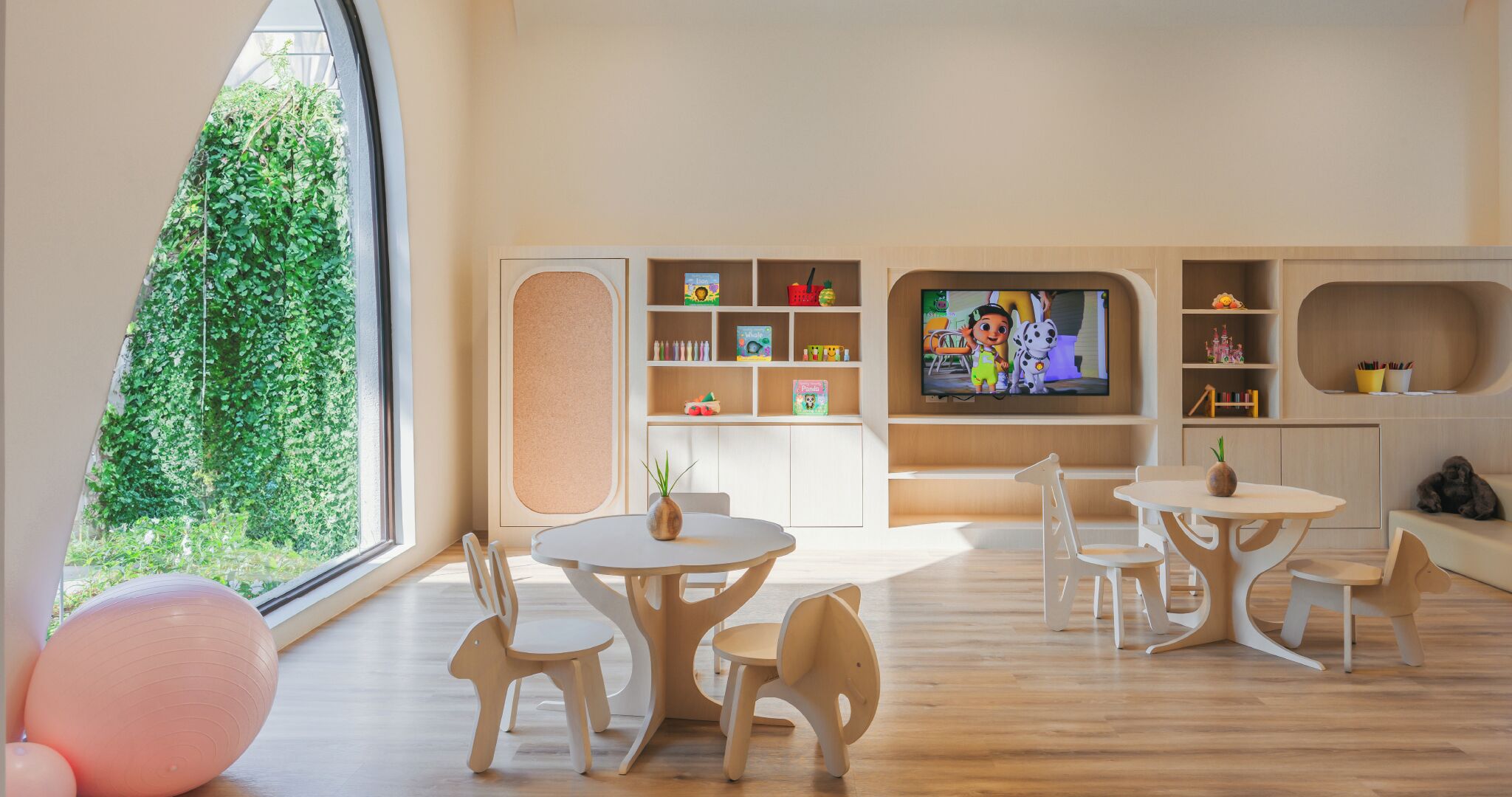 Un moderno cuarto de juegos para niños, con un amplio ventanal, muebles de madera y un televisor.