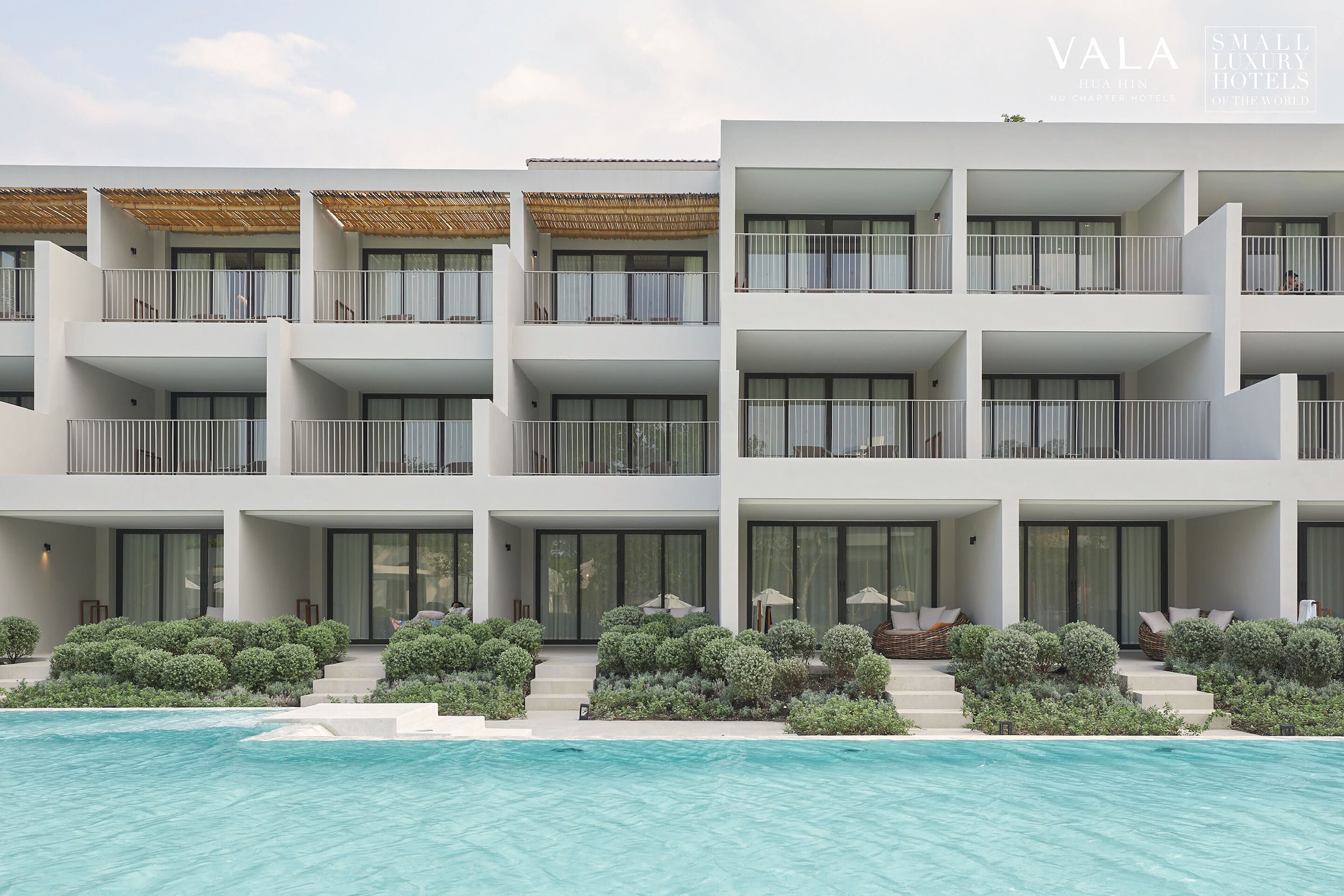 A modern hotel with multiple balconies, a swimming pool, and well-maintained landscaping.