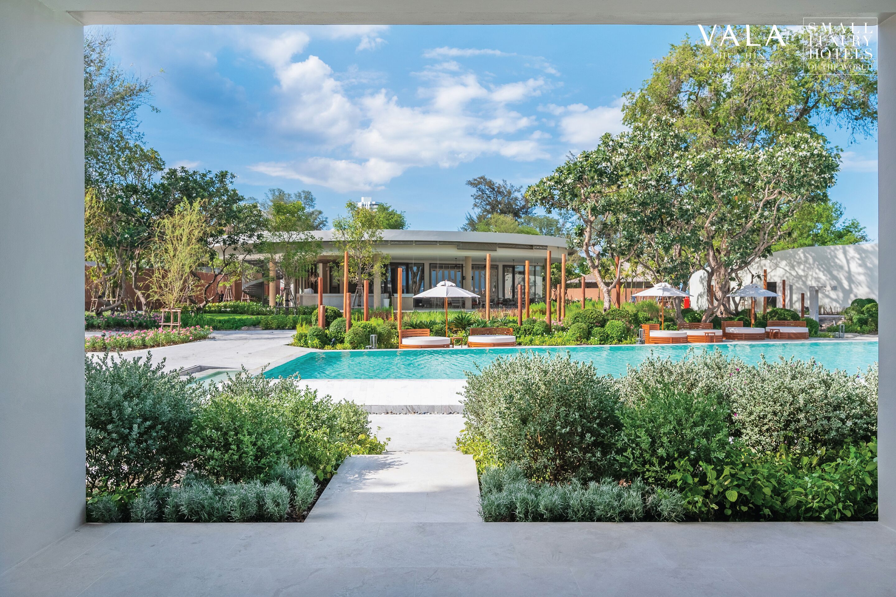 Un hôtel doté d’une piscine, d’un espace extérieur aménagé et d’une végétation luxuriante.