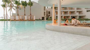A pool area with lounge chairs, palm trees, and a modern building with balconies.