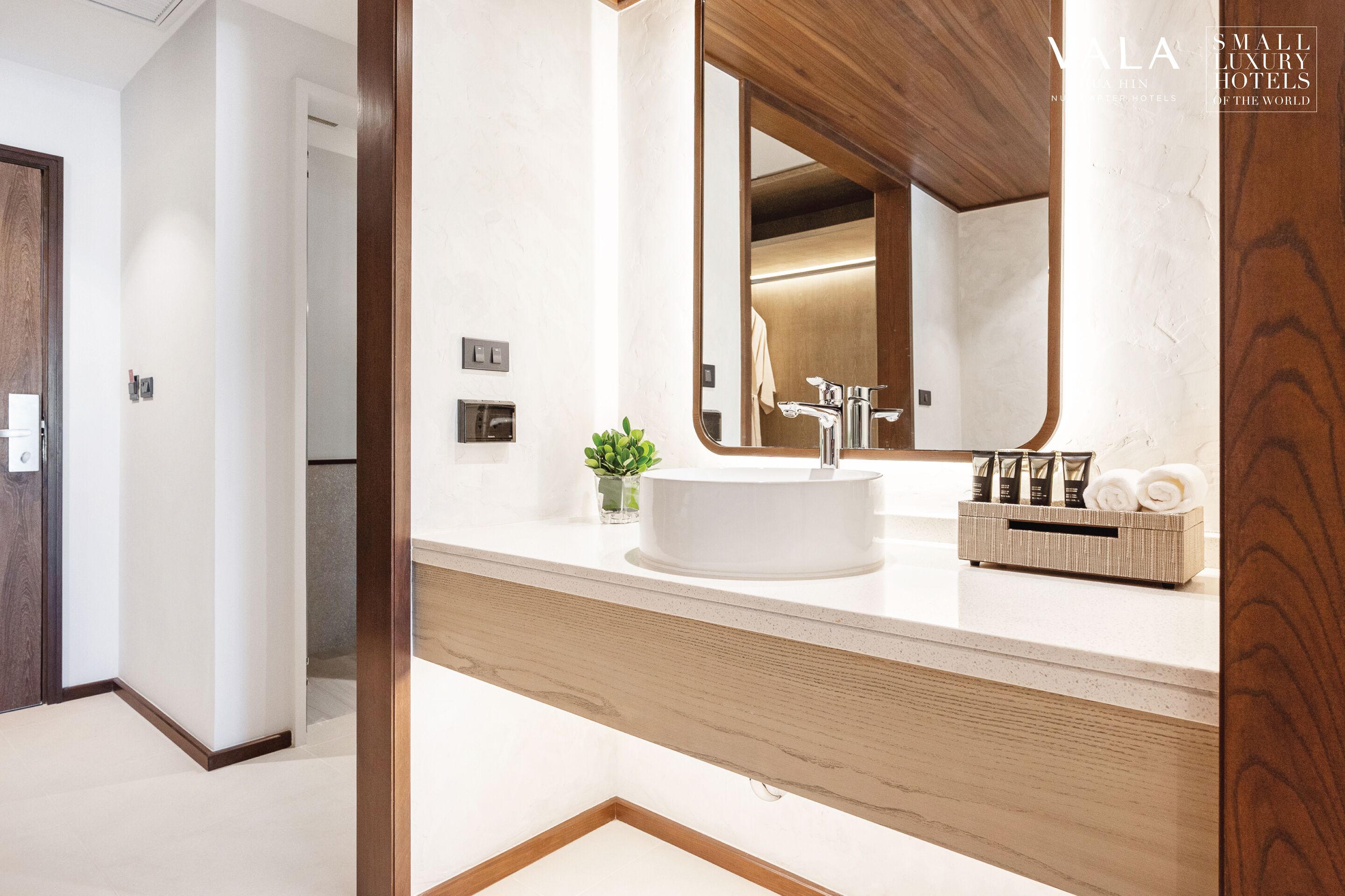 Een moderne badkamer met een grote spiegel, een rond wastafel en een houten wastafelmeubel.
