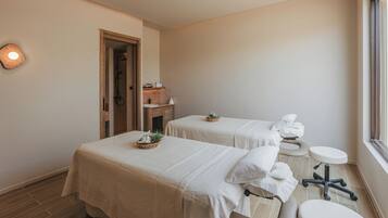 Un cuarto de spa con dos camillas, un lavamanos pequeño y una ventana.