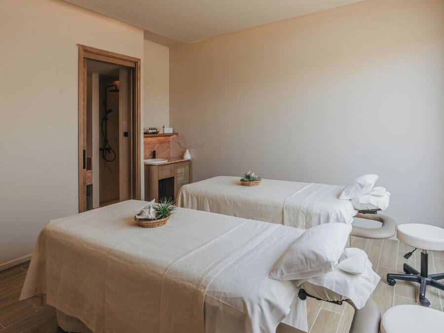 Un cuarto de spa con dos camillas, un lavamanos pequeño y una ventana.