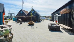 A waterfront area with wooden buildings, outdoor seating, and a clear sky. - Stunning home in Hejls (Hejls)