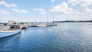 A marina with several boats docked, a pier extending into the water, and a clear sky with scattered clouds. - Stunning home in Hejls (Hejls)