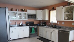 Una cocina con gabinetes blancos, estufa, microondas y lavavajillas.