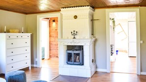 Una habitación con chimenea, piso de madera, un aparador blanco y una puerta que da a otra estancia.