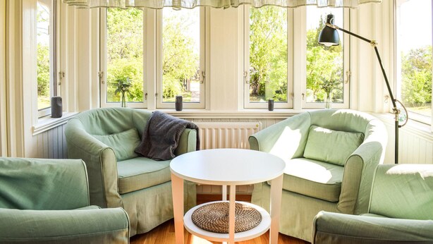 Una habitación con sofá verde, una mesa redonda y una lámpara de pie.