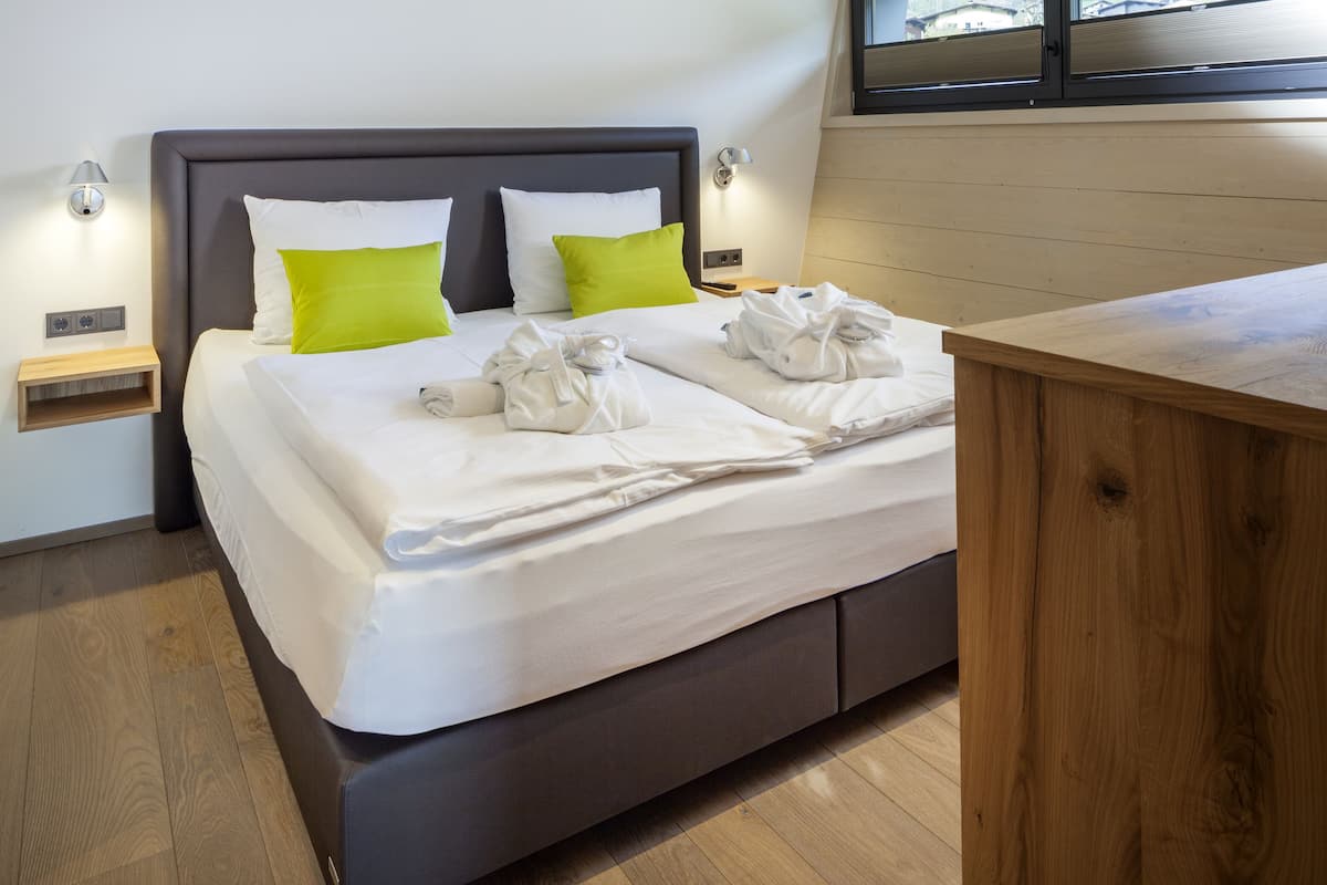 Un dormitorio moderno con una cama grande, dos mesitas de noche, un escritorio de madera y un ventanal con vistas.