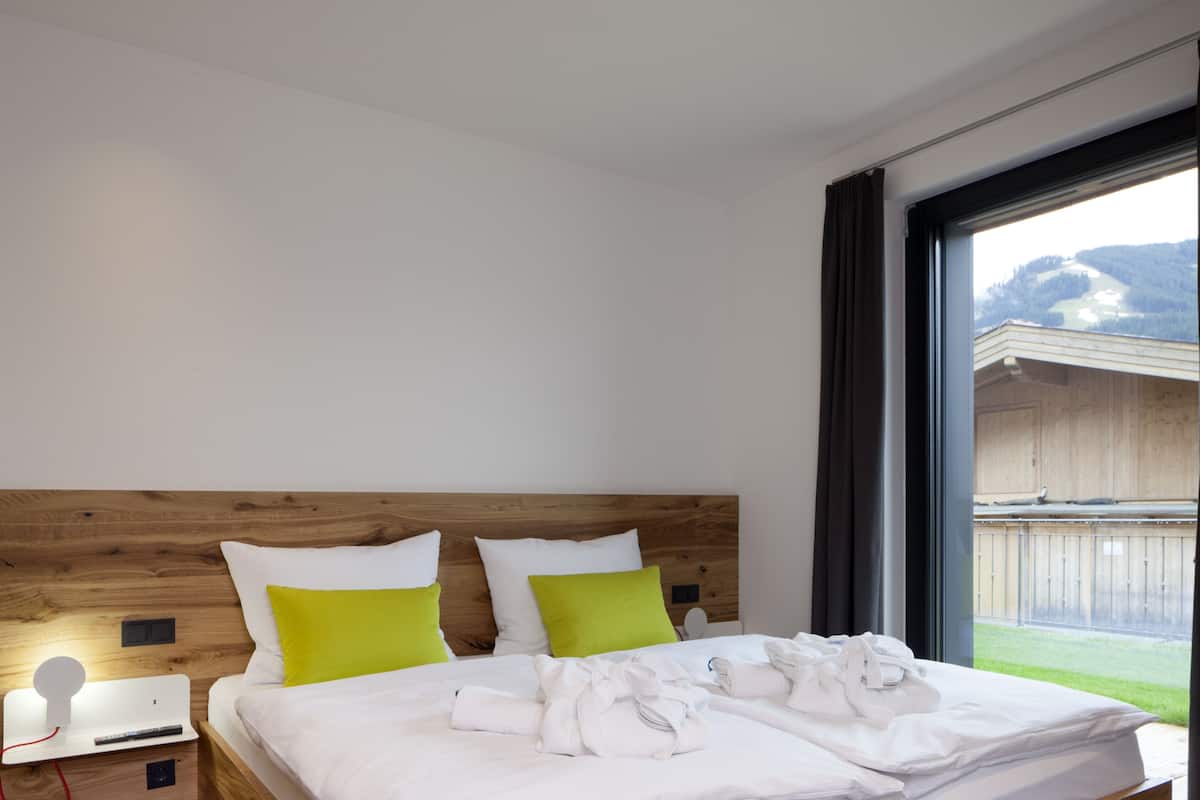 Un dormitorio moderno con cabecera de madera, una cama grande con ropa de cama blanca, dos almohadas y una cama bien tendida con toallas.