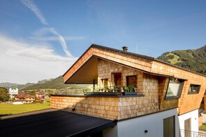 A modern house with a sloped roof, wooden exterior, and a balcony with plants. - Das Heimsitz (Brixen im Thale)
