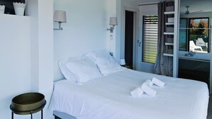 A bedroom with a bed, a ceiling fan, a bedside table, and a window with blinds.