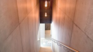 A modern staircase with wooden steps and a metal handrail, leading to a bright interior space.