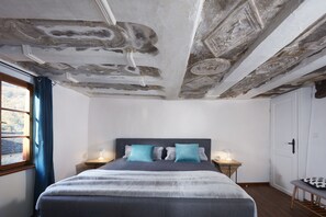 Une chambre à coucher avec un lit, deux tables de chevet avec des lampes, une fenêtre avec des rideaux et une porte.