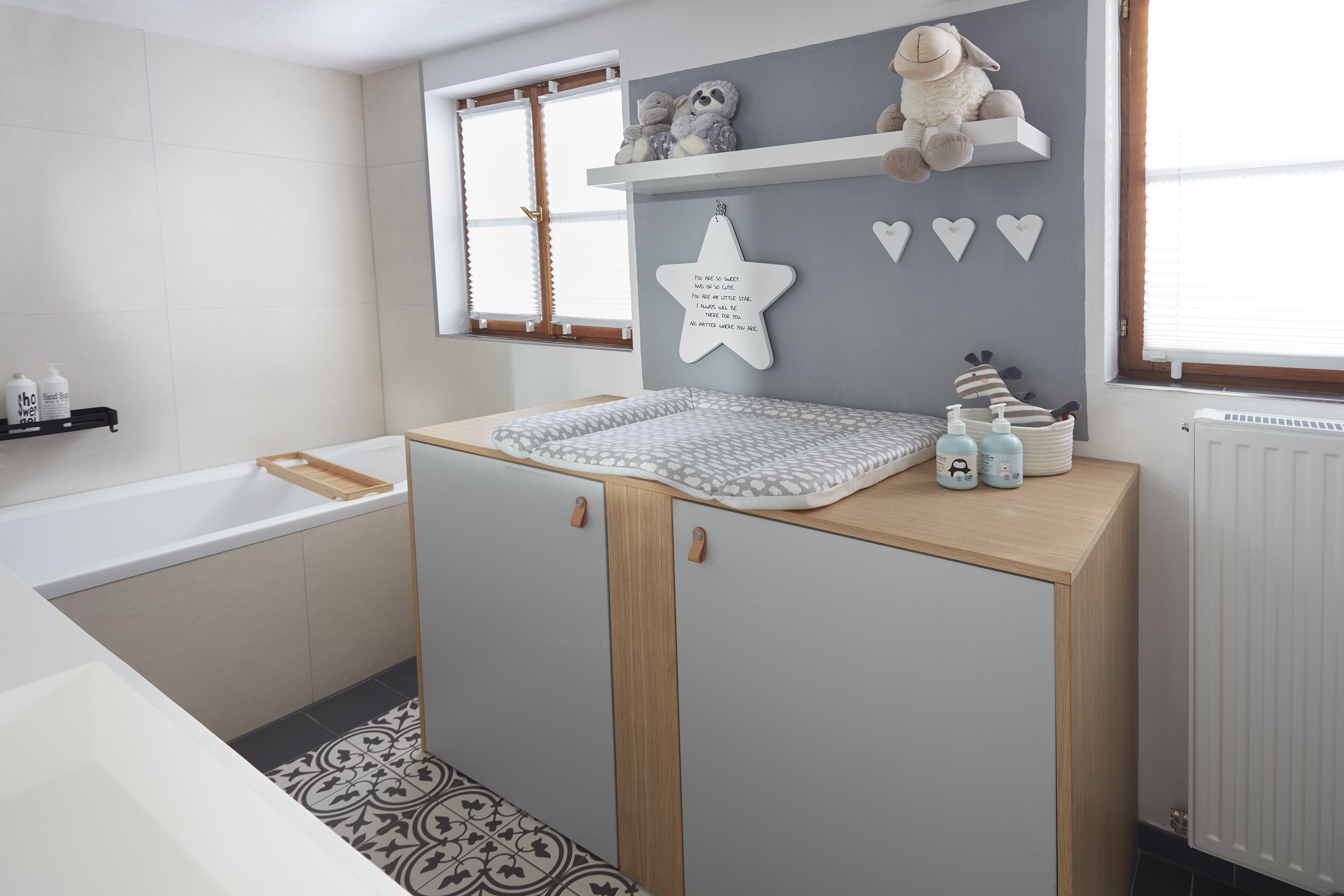 Een badkamer met een bad, een houten wastafelmeubel en een spiegel in de vorm van een ster, plus een raam met uitzicht.