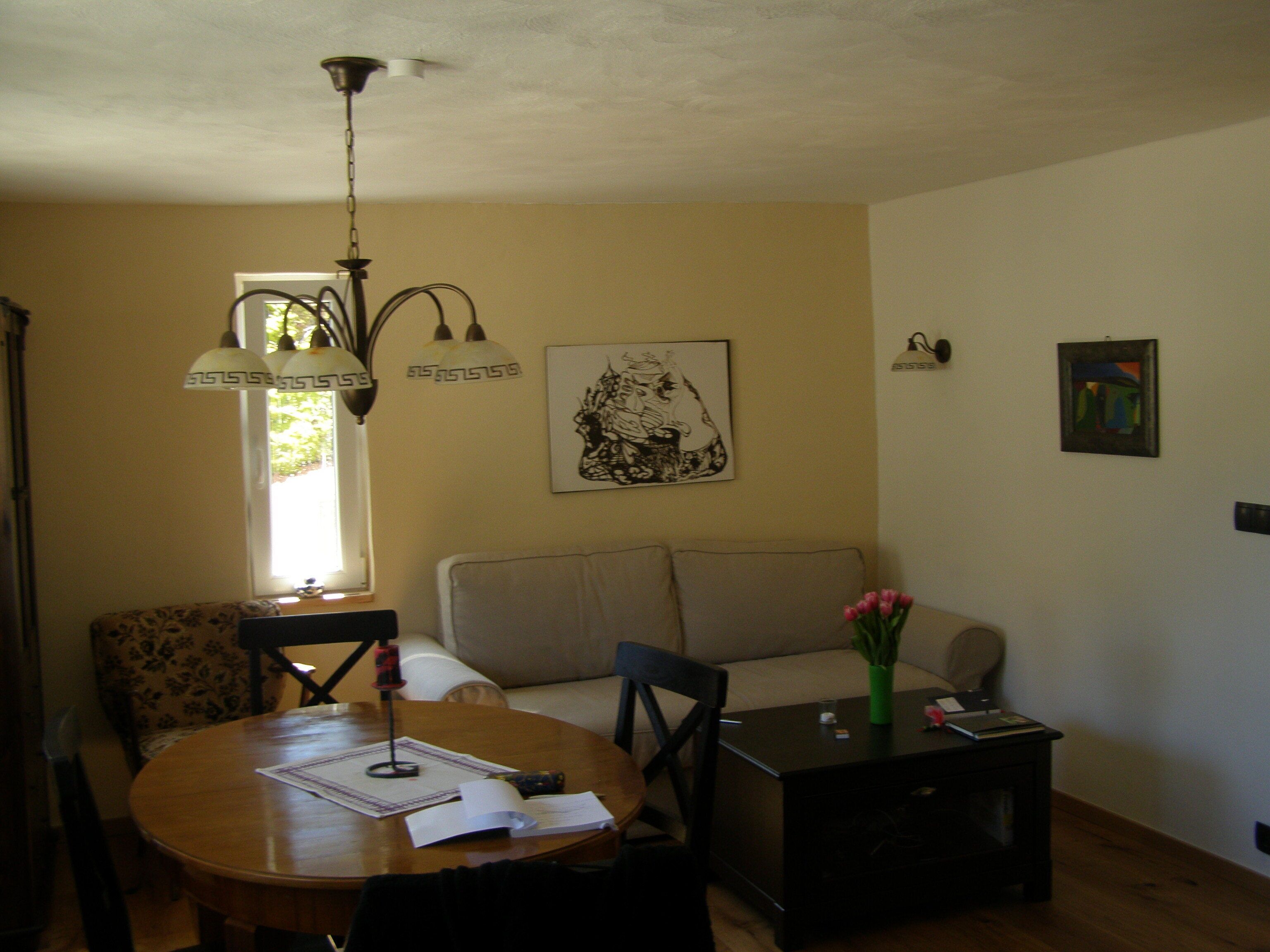 A living room with a sofa, a dining table with papers, a lamp, and artwork on the wall.