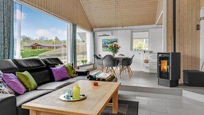 A modern living room with a sofa, dining table, and a kitchen area with a stove. - Beautiful home in Aabenraa with WiFi (Aabenraa)