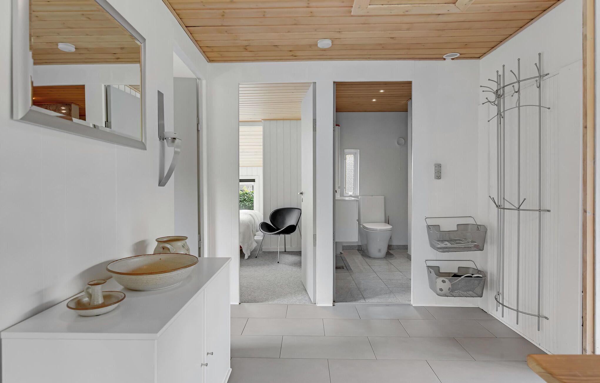Une salle de bain moderne avec un lavabo blanc, une chaise noire et un espace douche.