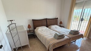 A bedroom with a bed, a ladder, a nightstand, an air conditioner, and a view through a window. - Villa El Olivo, rural villa with pool (Alcaucín)