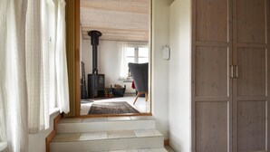 Escada que leva a uma sala de estar com lareira a lenha, uma poltrona e uma porta.