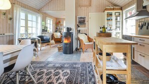 Een gezellig chaletinterieur met een open haard, houten meubels en een keukenhoek.