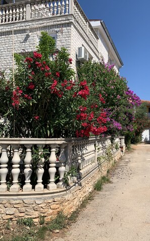 Traditional stone building with a classic balcony and lush surroundings.