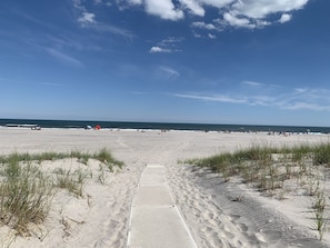 Una playa arenosa con cielo despejado y algunas personas a lo lejos.
