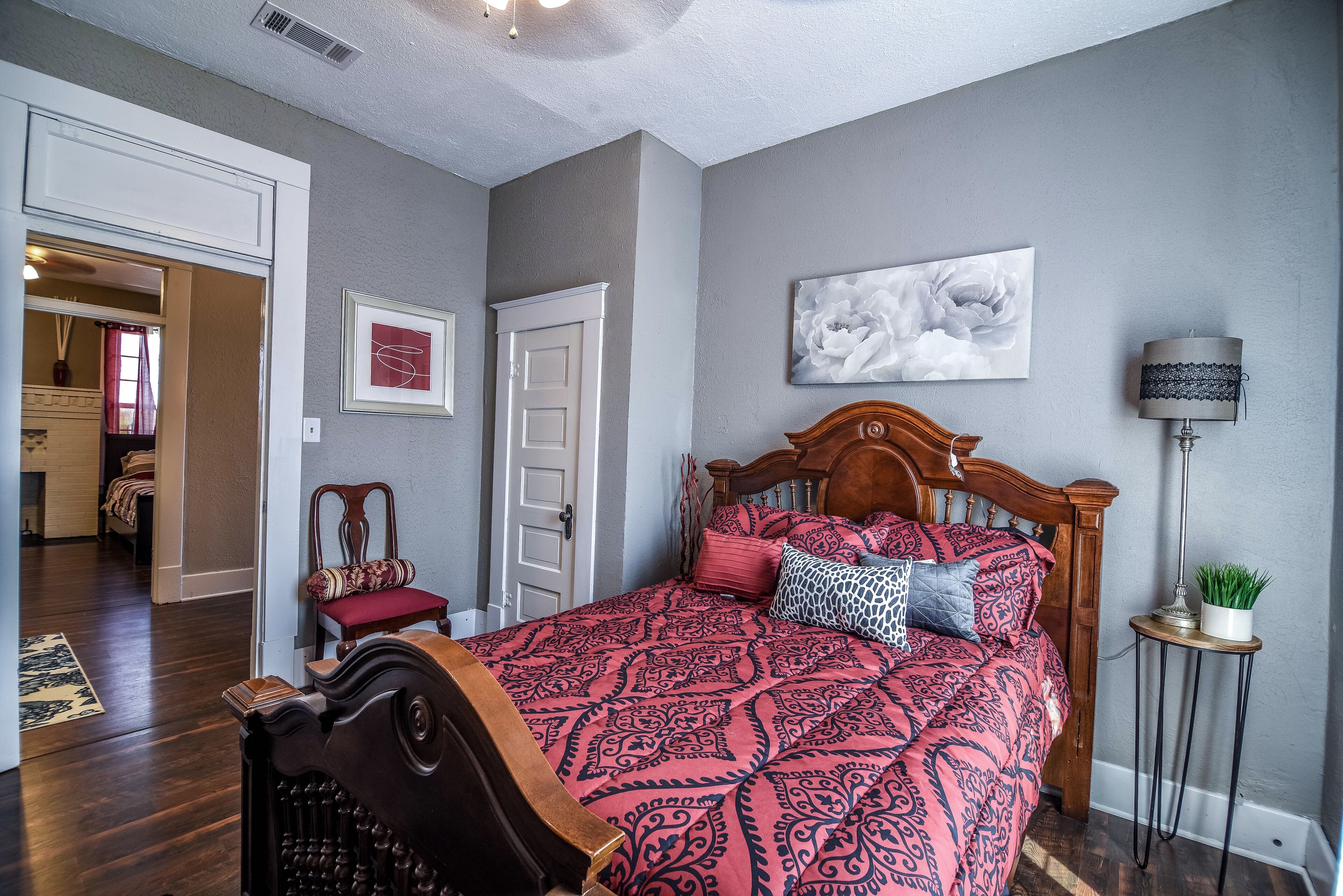 Una camera da letto con un letto in legno, un comodino, una lampada e un quadro appeso al muro.